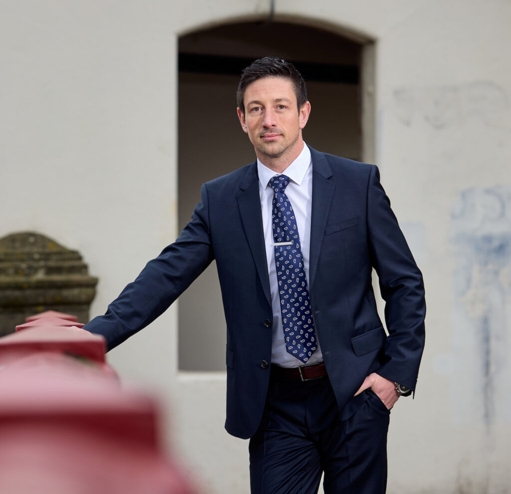 Dean Taylor in a Suit Leaning on a Fence